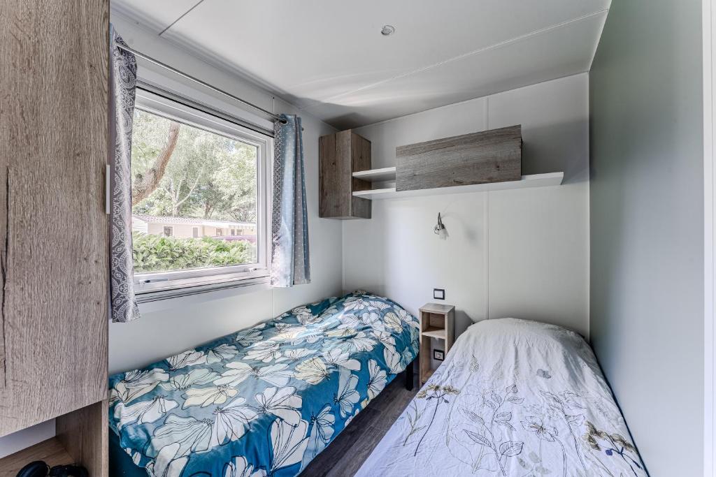une petite chambre avec un lit et une fenêtre dans l'établissement Mobil-home camping Gastes Landes, à Gastes