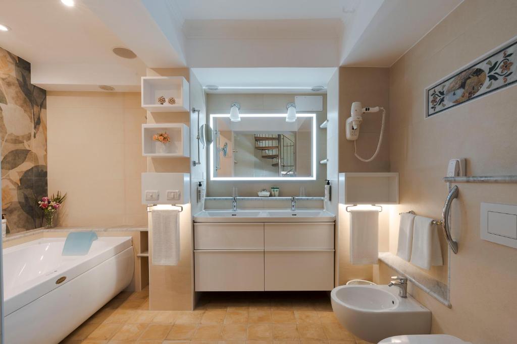 une salle de bain avec une baignoire, un lavabo et un miroir dans l'établissement Hotel Villa Schuler, à Taormine