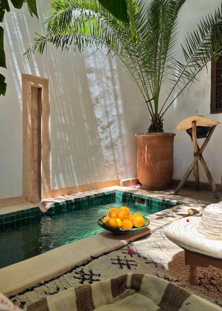 un bol d'oranges sur une table à côté d'une piscine dans l'établissement Riad Dar Zaman, à Marrakech