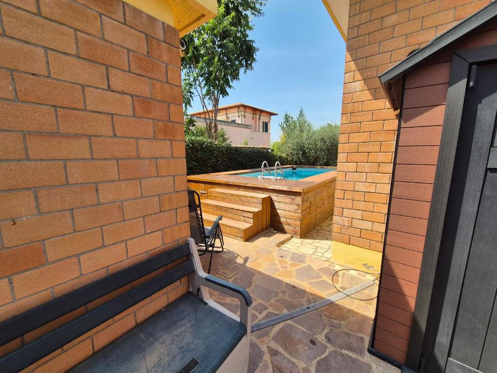 un mur de briques avec un banc à côté d'une piscine dans l'établissement Moderna villa con piscina a due Passi dal Golf Club, à Pavona