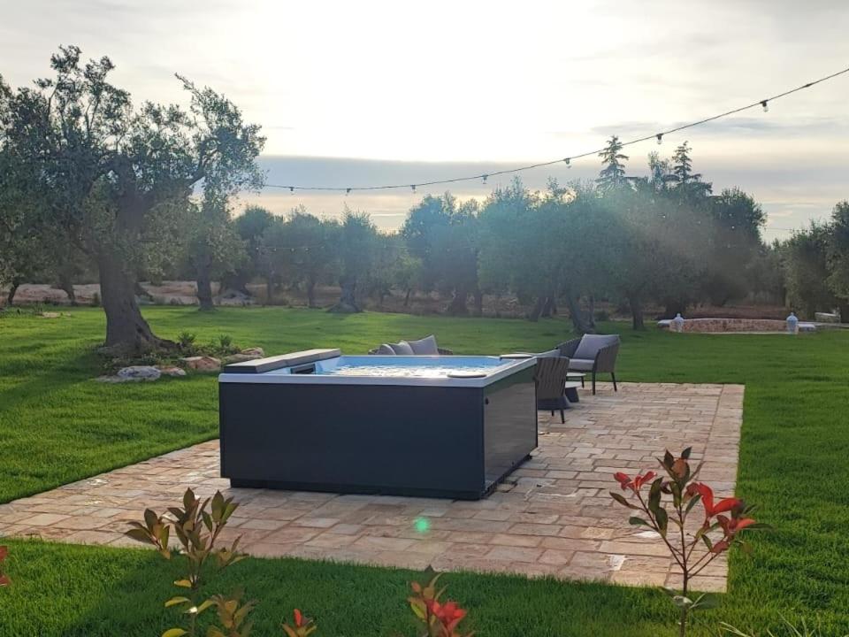 un patio avec un jacuzzi au milieu d'un champ dans l'établissement Trulli Vecchia Corte Monopoli, à Monopoli