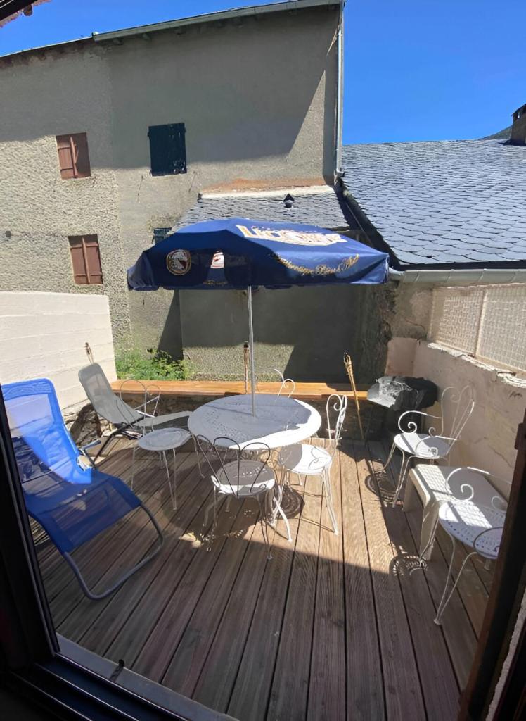 une table, des chaises et un parasol sur une terrasse dans l'établissement Maison village proche Andorre et stations de ski, à Porté-Puymorens