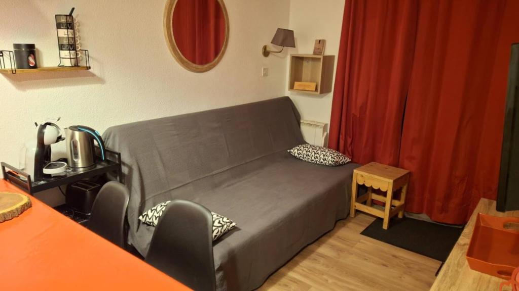 une chambre avec un lit et un rideau rouge dans l'établissement CŒUR D'ALTAÏR RISOUL 1850 Appartement T2 confortable skis aux pieds, à Risoul