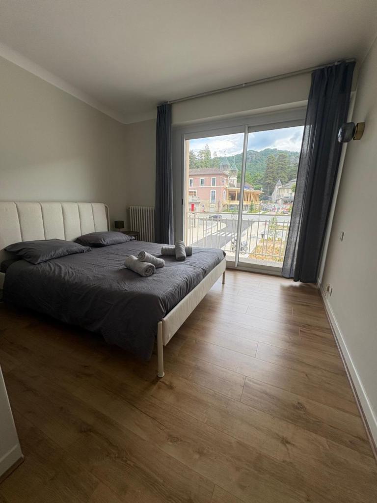 une chambre avec un grand lit et une grande fenêtre dans l'établissement Les Balcons du Couloubret, à Ax-les-Thermes