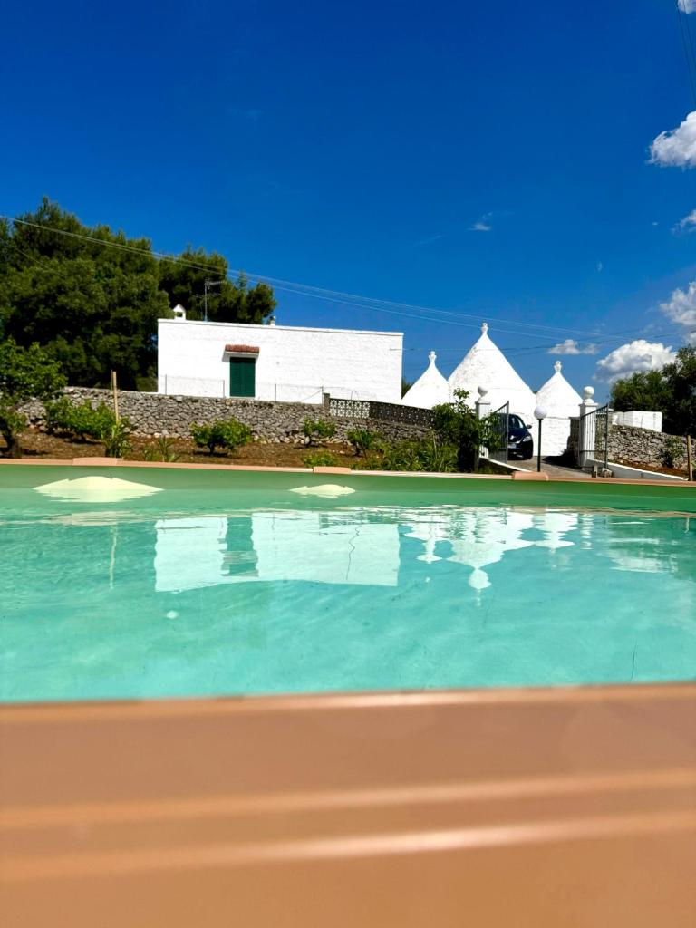 une piscine avec un bâtiment blanc en arrière-plan dans l'établissement Trullo Simona - Luxury Relax House, à Ostuni