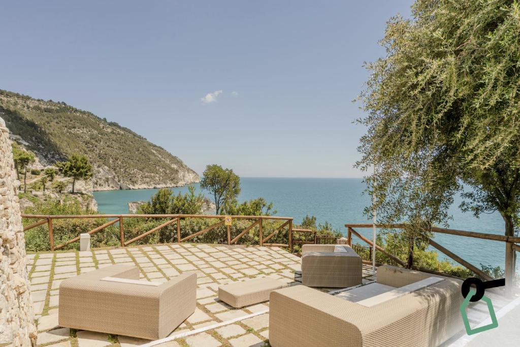 un patio avec des chaises et une vue sur l'océan dans l'établissement HOTIDAY Room Collection - Mattinata Faraglioni, à Mattinata