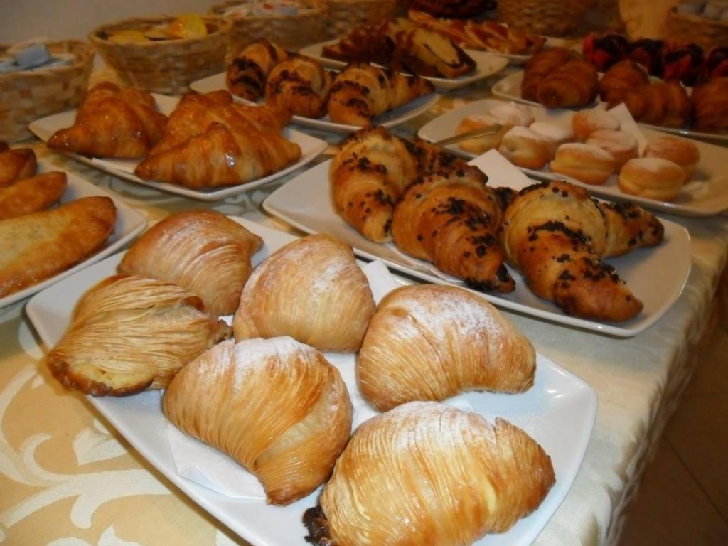 une table garnie d'assiettes de viennoiseries et de croissants dans l'établissement Magnolia Hotel Vieste, à Vieste