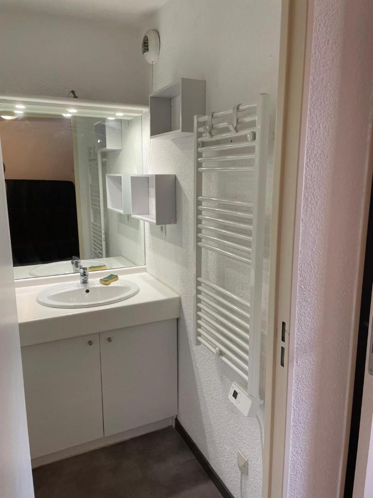 une salle de bain blanche avec un lavabo et un miroir dans l'établissement La Foux d'Allos, à Allos