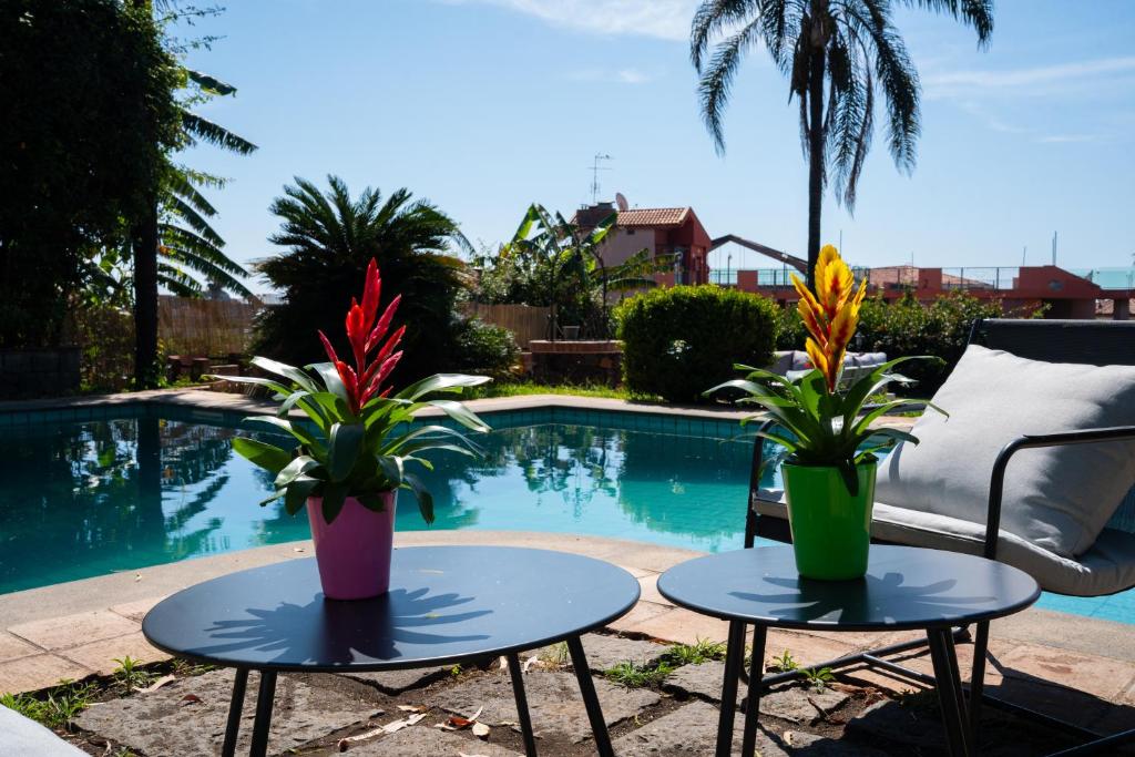 deux tables avec des fleurs dessus à côté d'une piscine dans l'établissement Silvanae Pool Villa, à Aci Castello