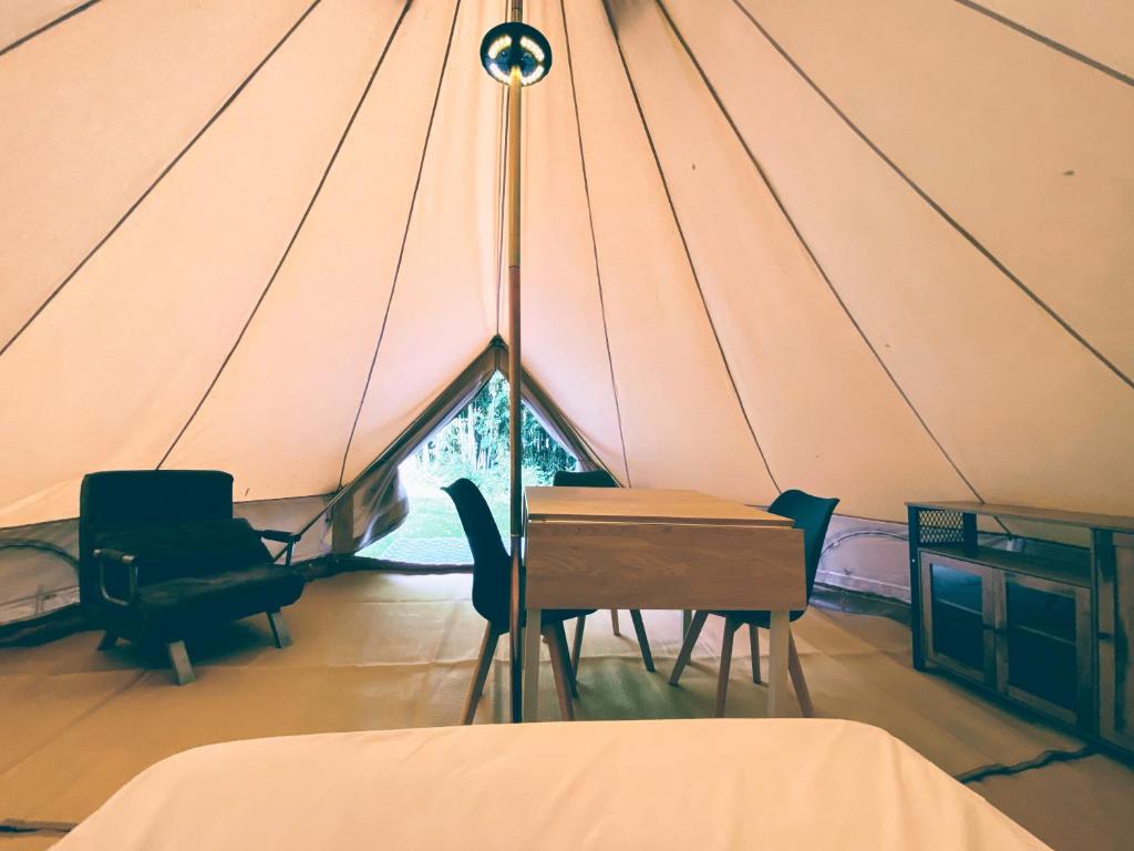une chambre avec une table et des chaises dans une tente dans l'établissement Camping les Avenières, à Manthes