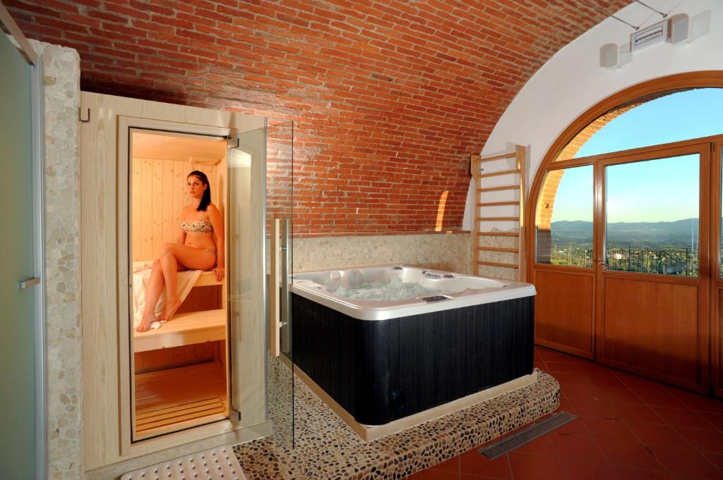 une femme est assise dans une baignoire dans une salle de bains dans l'établissement La Pietra Piana Villa panoramica con spa e piscina naturale vicino Firenze, à Reggello