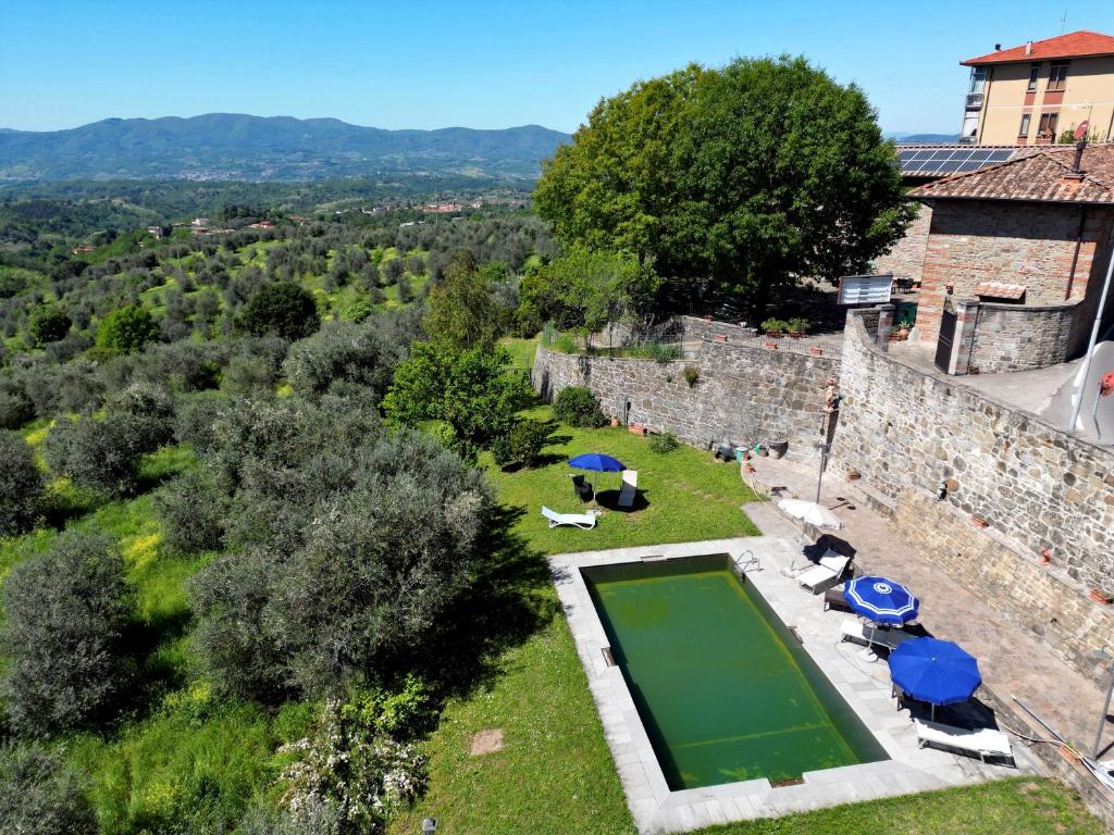 une vue aérienne d'un château avec une piscine et des parasols dans l'établissement La Pietra Piana Villa panoramica con spa e piscina naturale vicino Firenze, à Reggello