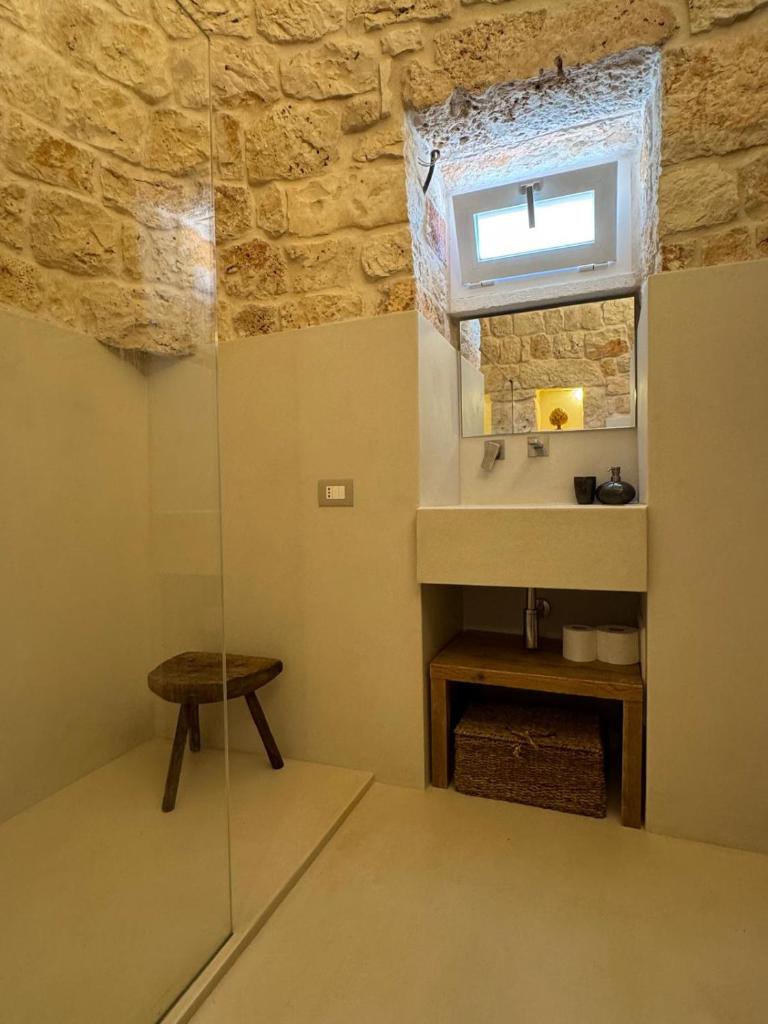 une salle de bain avec un lavabo et une douche en verre dans l'établissement Trullo di Theo, à Ostuni