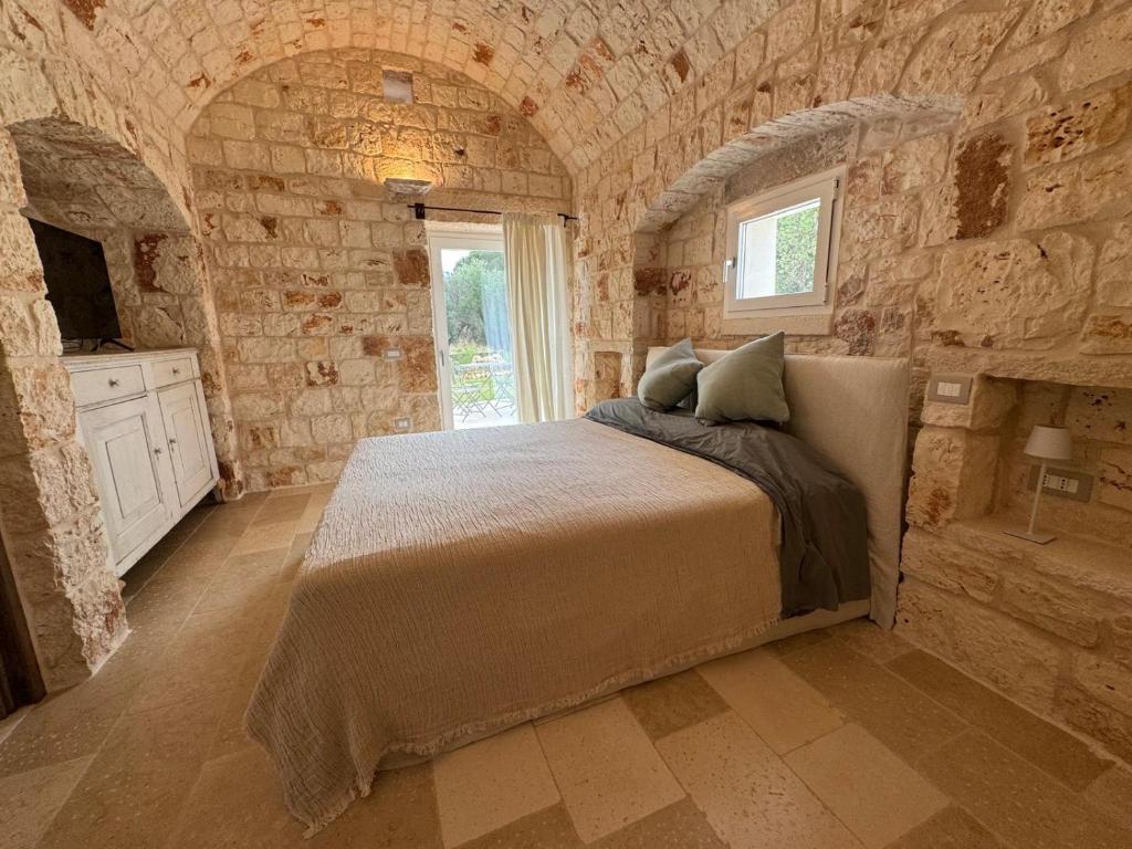 une chambre avec un lit dans un mur de pierre dans l'établissement Trullo di Theo, à Ostuni