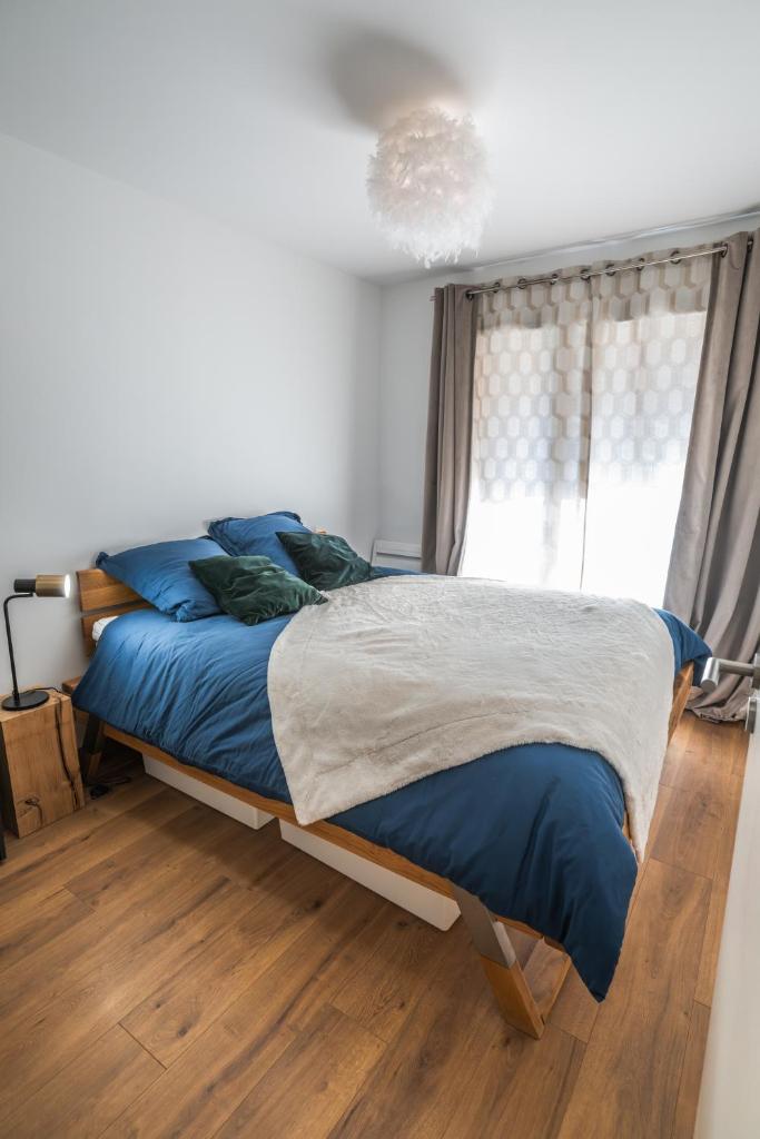 une chambre avec un lit avec des draps bleus et une fenêtre dans l'établissement Le chalet des étoiles, à La Mongie