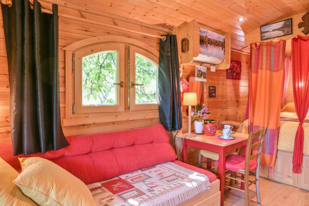 - un salon avec un canapé rouge dans une cabane en rondins dans l'établissement Roulotte de bohême - Praline, à Truison