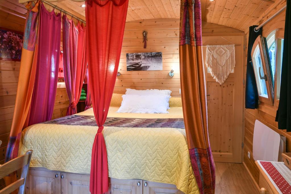 une chambre dans une petite maison avec des rideaux autour d'un lit dans l'établissement Roulotte de bohême - Praline, à Truison