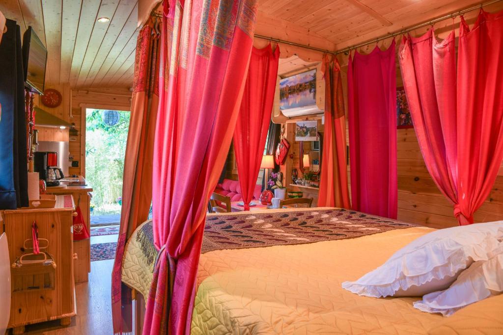 - une chambre avec un lit doté de rideaux rouges dans l'établissement Roulotte de bohême - Praline, à Truison