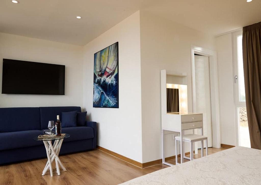 un salon avec un canapé bleu et une télévision dans l'établissement Borgo Rosso Terra, à Gallipoli