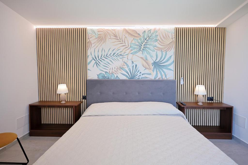 une chambre avec un grand lit et deux tables de nuit dans l'établissement Dimora Masi di GN Real Escapes, à Castellammare del Golfo