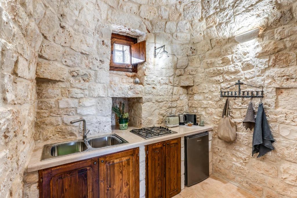 une cuisine avec un évier et un mur en pierre dans l'établissement Trullo La Sacchina, à Ostuni