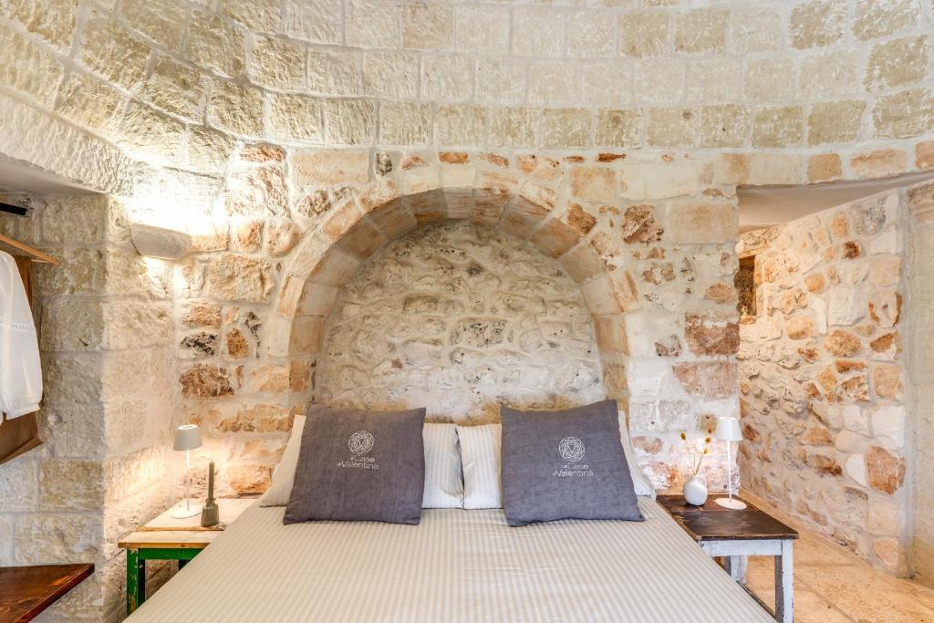 une chambre avec un lit dans un mur de pierre dans l'établissement Trullo La Sacchina, à Ostuni