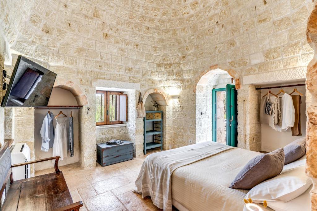une chambre avec un grand lit dans un mur de pierre dans l'établissement Trullo La Sacchina, à Ostuni