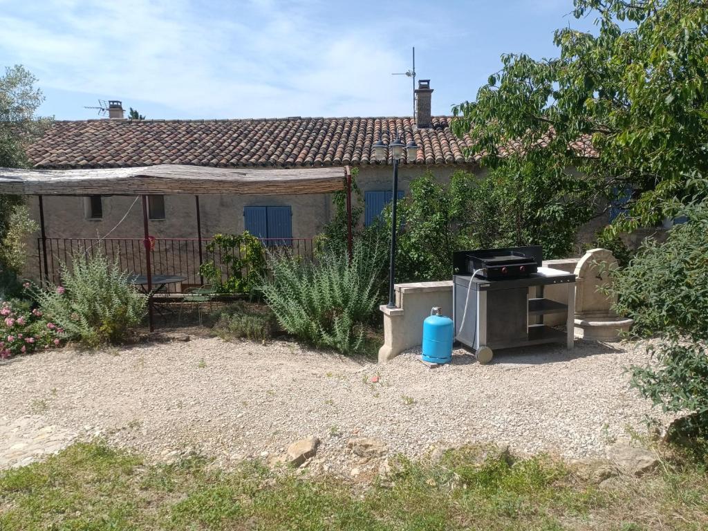 une maison avec un grill en face d'une cour dans l'établissement Gîte en provence au coeur des vignes, à Villedieu