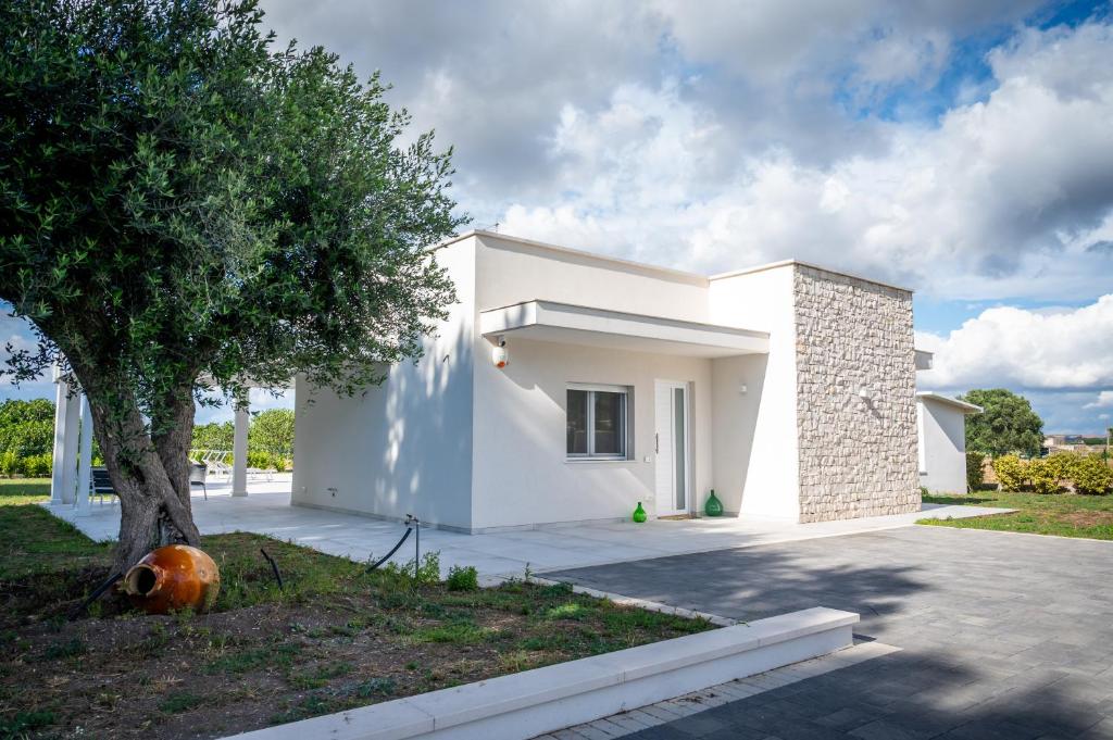 une maison blanche avec un arbre devant dans l'établissement LikeHome Taranto - 2 ville indipendenti, à Tarente