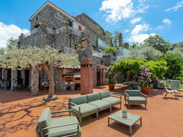 un grand bâtiment avec des canapés et des tables dans une cour dans l'établissement Villa Carolina Sorrento Private Heated Pool and Sea View, à Sorrente