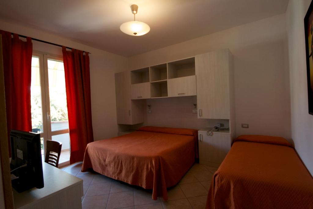 une chambre d'hôtel avec deux lits et une fenêtre dans l'établissement Hotel Il Pino, à San Vincenzo