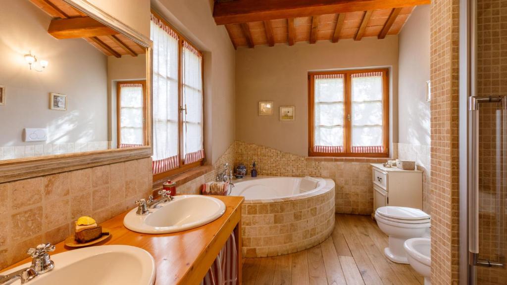 une salle de bain avec deux lavabos et une baignoire et des toilettes dans l'établissement La Tana del Ghiro 18, Emma Villas, à Ravenne