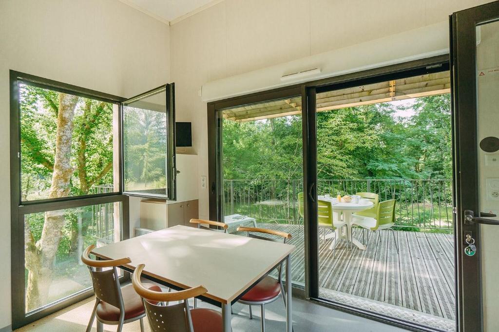 une salle à manger avec une table et des chaises et un balcon dans l'établissement Huttopia Beaulieu sur Dordogne, à Beaulieu-sur-Dordogne