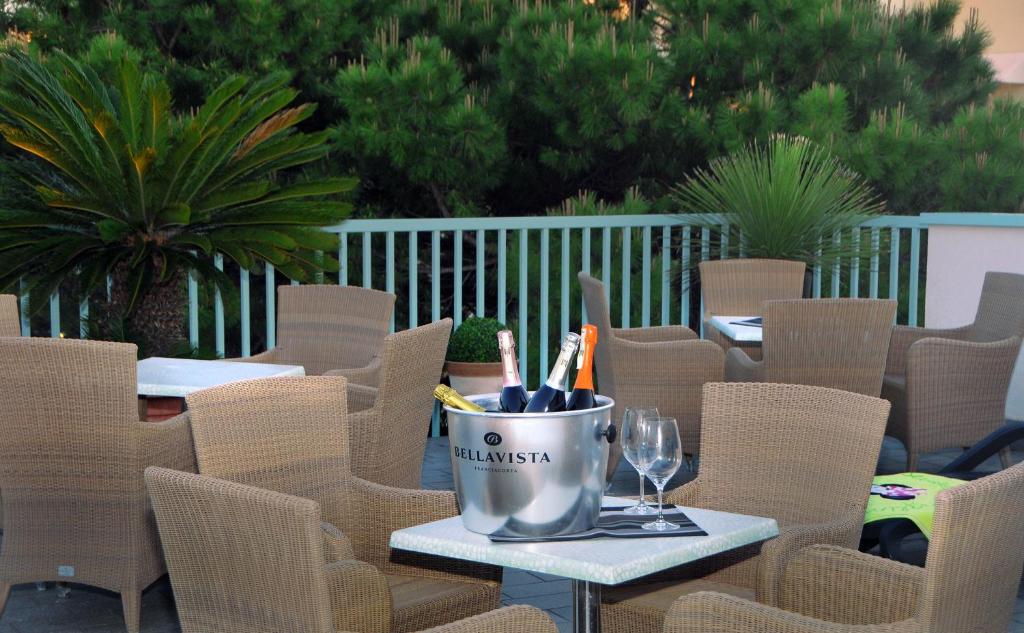 une table avec des chaises et un seau de verres à vin dans l'établissement Hotel Raffaello, à Caorle