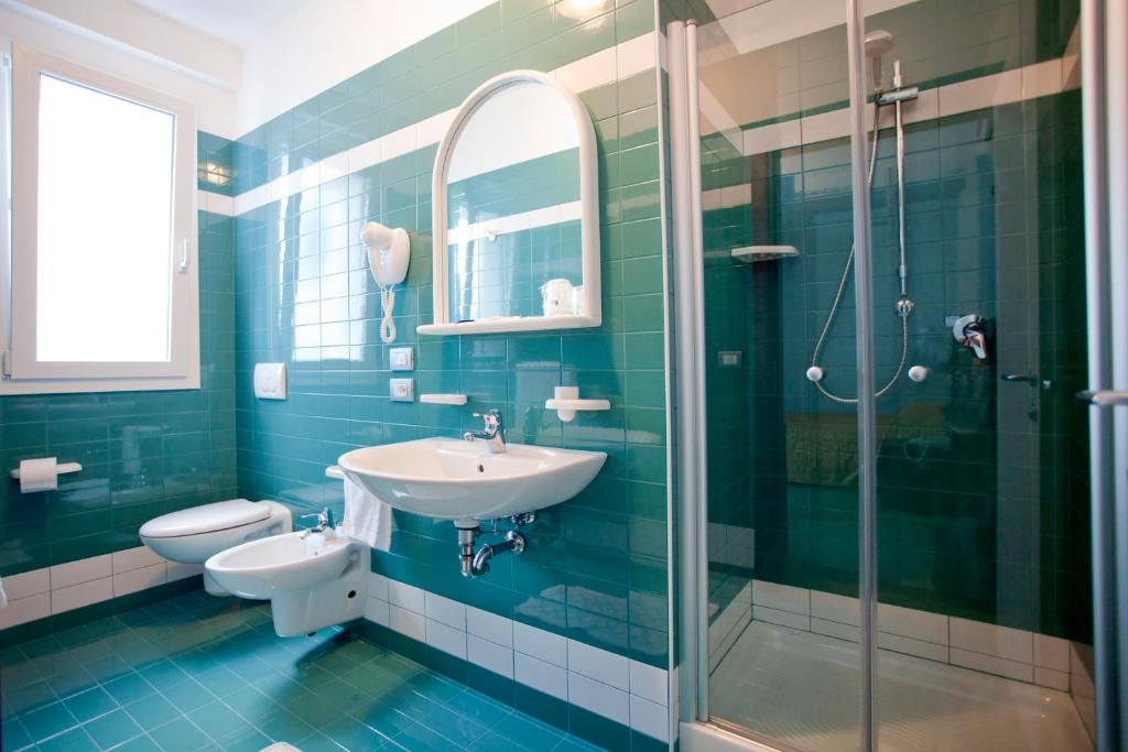 une salle de bain avec un lavabo, des toilettes et une douche dans l'établissement Hotel Raffaello, à Caorle