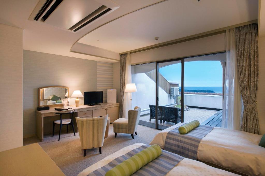 Cette chambre comprend deux lits, un bureau et un balcon. dans l'établissement Izumigo Hotel Altia Toba, à Toba