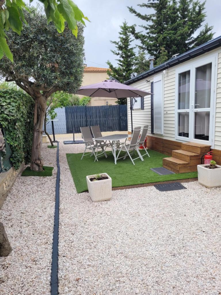 un patio avec des chaises, une table et un parasol dans l'établissement Mobil home de Patricia et Franck à Sigean, à Sigean
