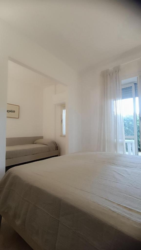 une chambre blanche avec un grand lit et une fenêtre dans l'établissement Residence Airone, à Orbetello
