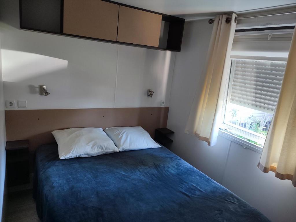 une chambre avec un lit avec une couverture bleue et une fenêtre dans l'établissement Camping DEL MAR 4 Étoiles à ARGELÈS SUR MER Mobil-Home Cosy en 3Ch au calme, à Argelès-sur-Mer 31 autres photos
