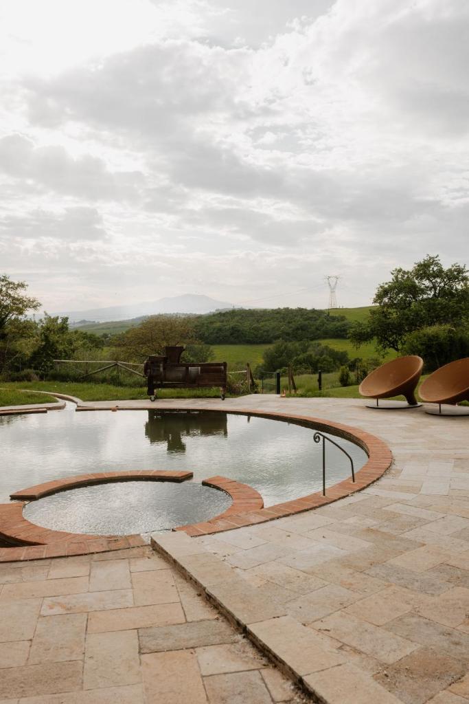 un bassin d'eau avec deux chaises et un banc dans l'établissement Podere la Piscina acqua calda RestArt, à San Casciano dei Bagni