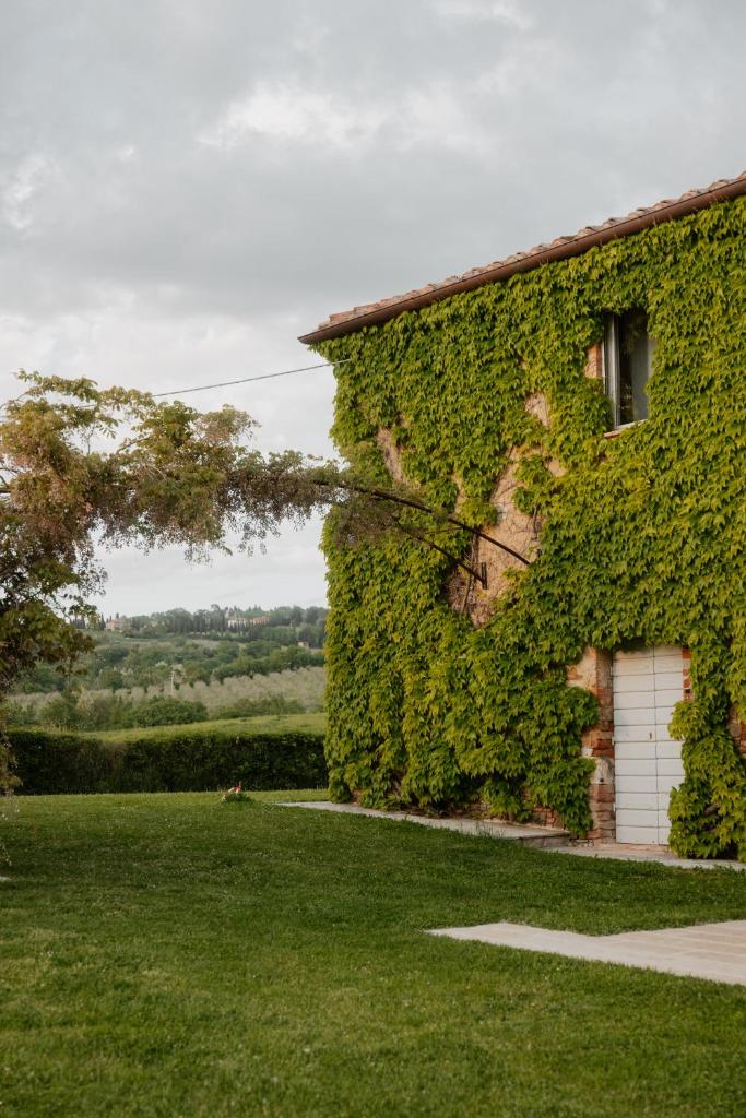 un bâtiment couvert de lierre avec un garage blanc dans l'établissement Podere la Piscina acqua calda RestArt, à San Casciano dei Bagni