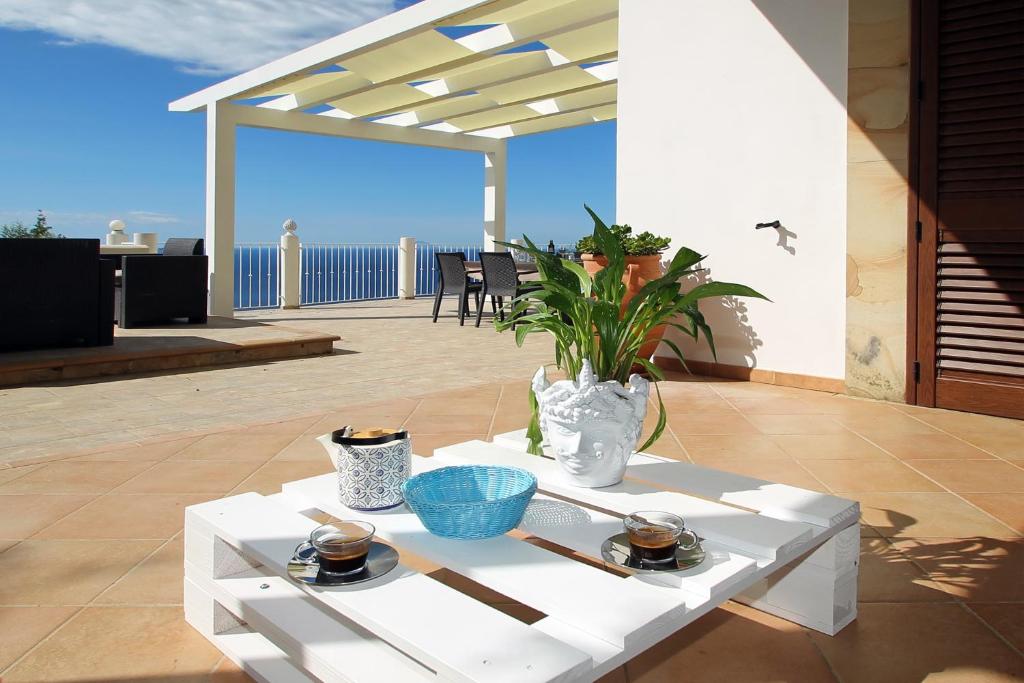 une table basse blanche sur une terrasse avec vue sur l'océan dans l'établissement Villa DAMMUSO by Local House - private villa infinity pool & seaview, à Santo Stefano di Camastra