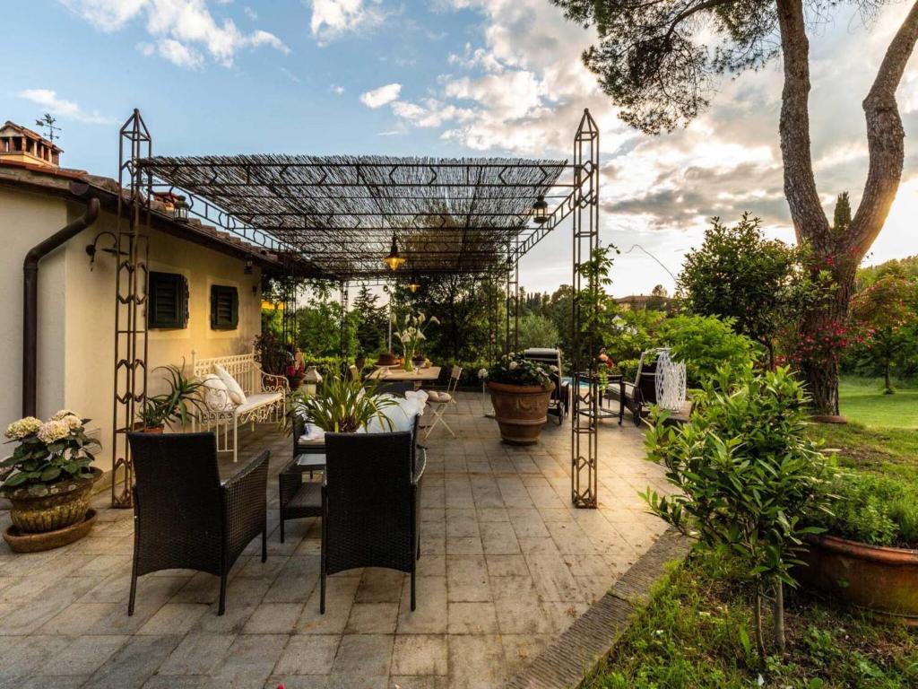 un patio avec une pergola et des tables et des chaises dans l'établissement Farmhouse in Pescia with Pool and Gardens, à Pescia
