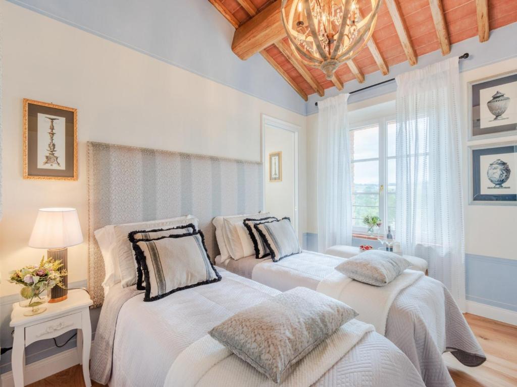 - 2 lits dans une chambre dotée d'un lustre dans l'établissement Villa in Lucca with Pool and Scenic Views, à Montecarlo