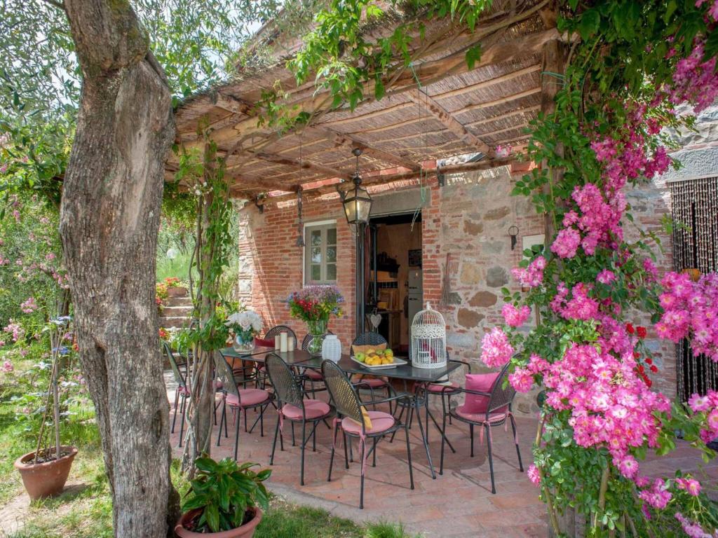 - une terrasse avec une table, des chaises et des fleurs dans l'établissement Villa in Lucca with Pool near Tuscan Coast, à Aquilea