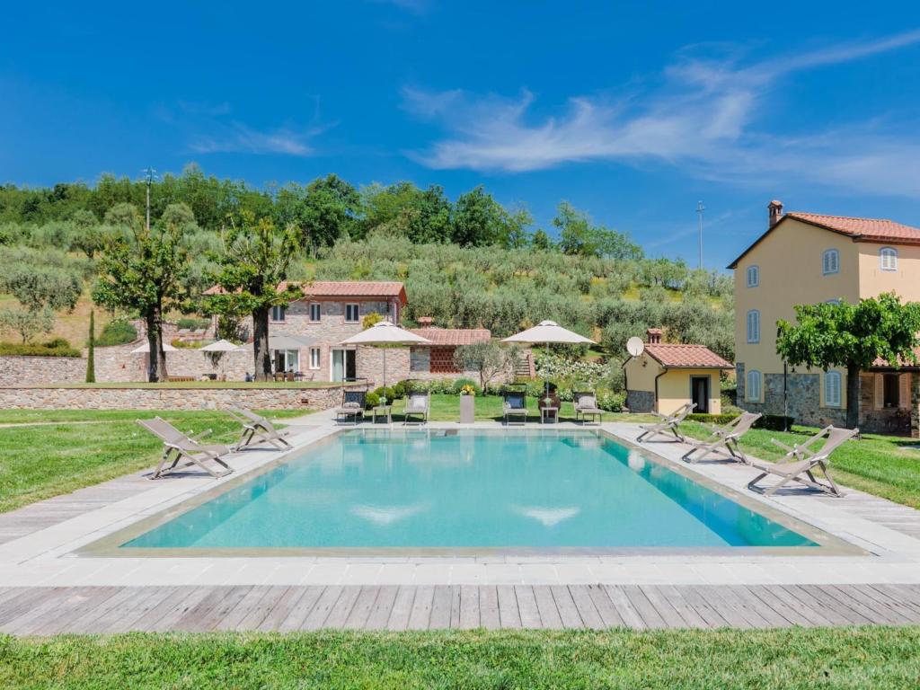 une piscine avec des chaises et une maison en arrière-plan dans l'établissement Farmhouse in Lucca with Infinity Pool, à San Ginese