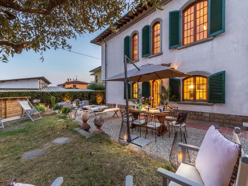 une terrasse avec une table et un parasol en face d'une maison dans l'établissement Villa in Lucca with Pool and Countryside Views, à Cappella