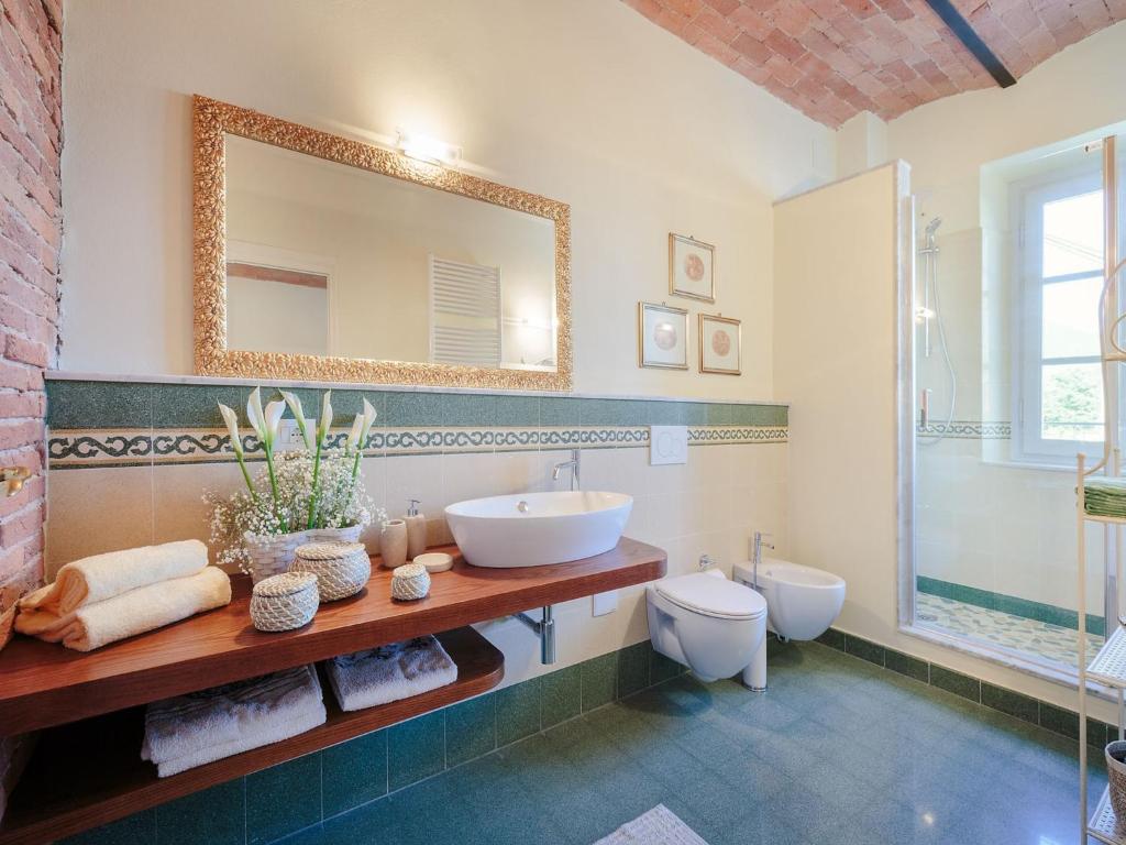 une salle de bain avec un lavabo, des toilettes et un miroir dans l'établissement Villa in Marlia with Pool near Lucca, à Marlia