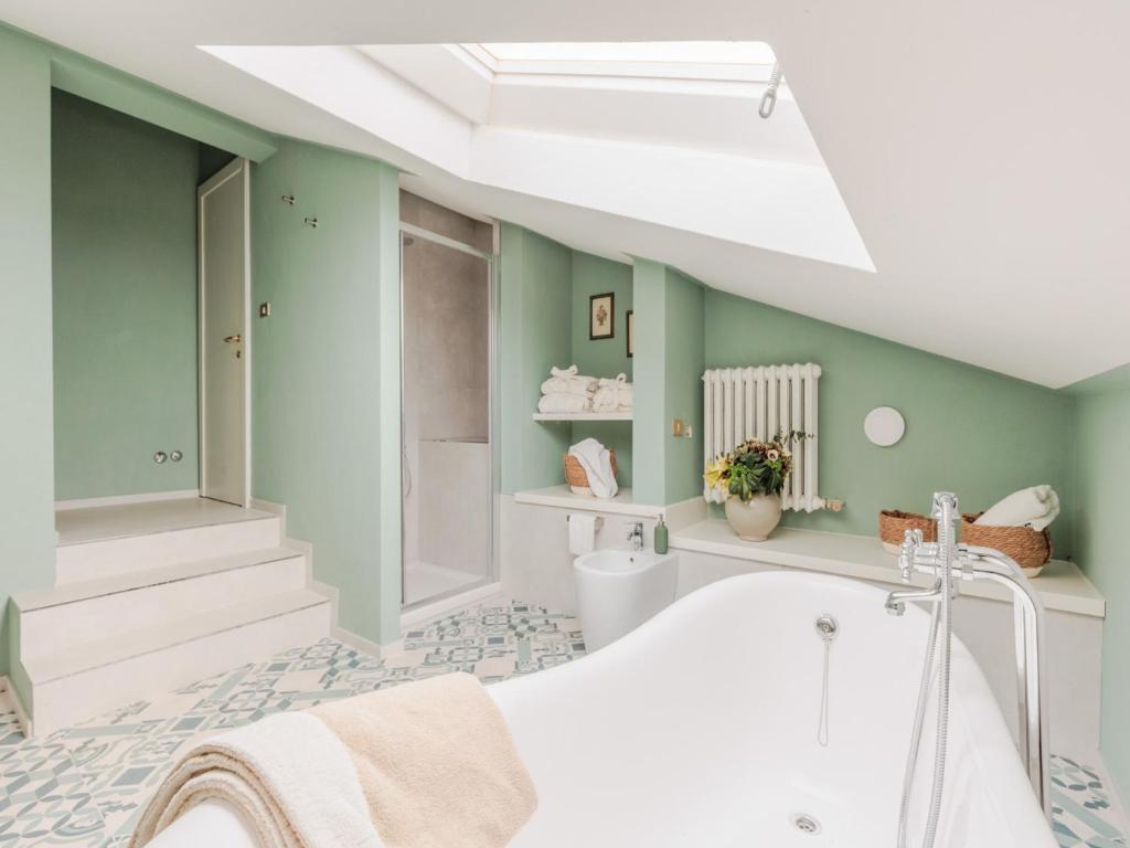 La salle de bains est pourvue d'une baignoire blanche et de murs verts. dans l'établissement Villa in Tuscany with Private Pool and Charm, à Bientina