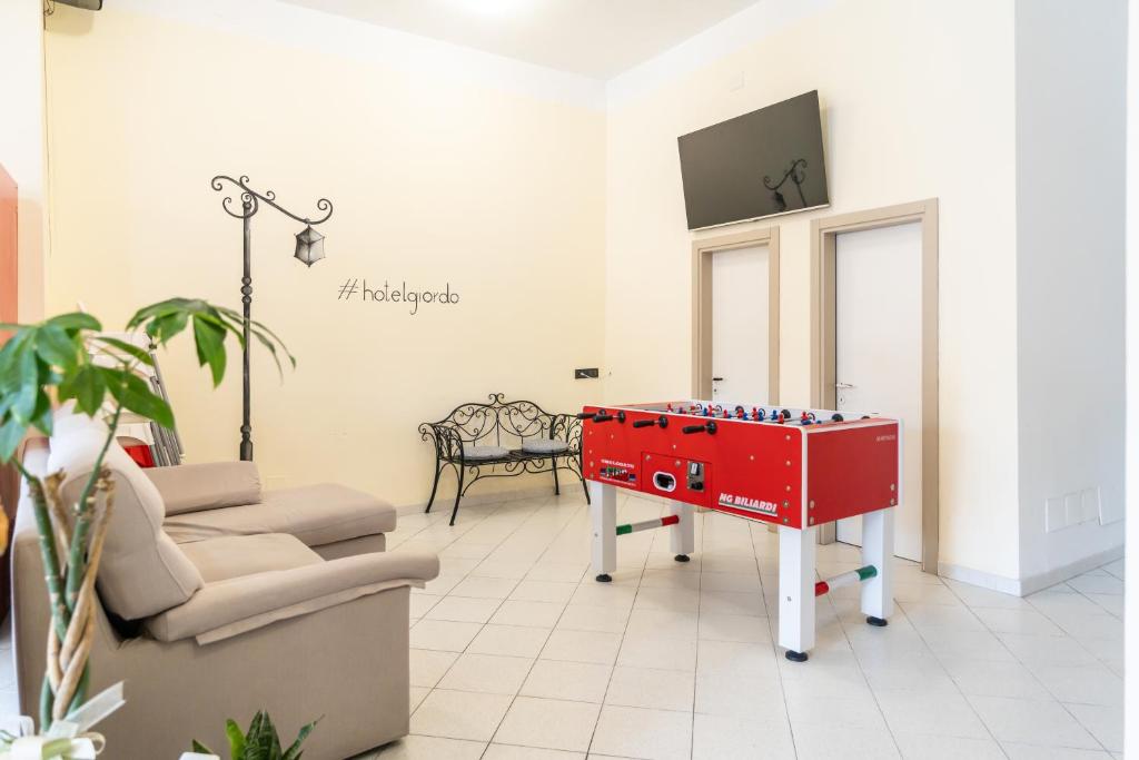un salon avec une table rouge et une télé dans l'établissement Hotel Giordo, à Rimini